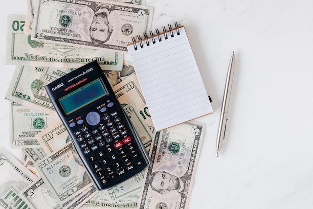 calculator notepad cash money on white desk investment