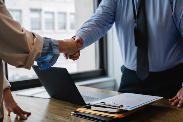 investment property management two people shaking hands over desk