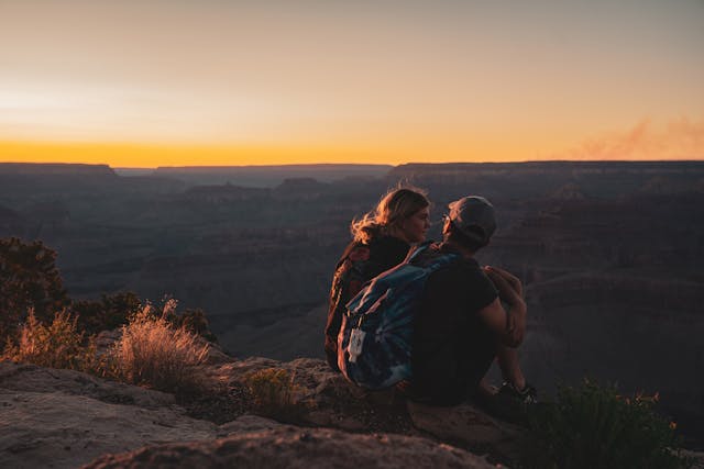 man-and-man-sitting-on-mountain-edge