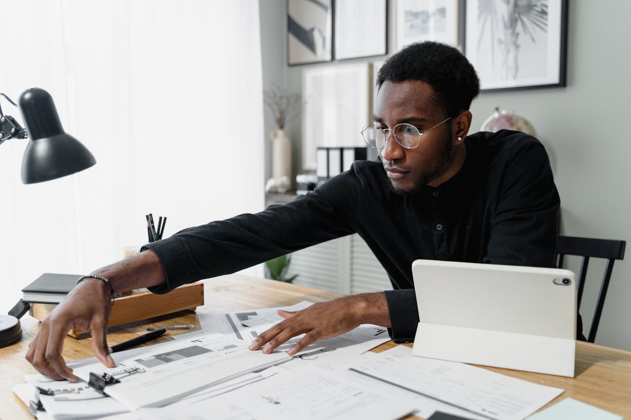 person reaching for papers on desk
